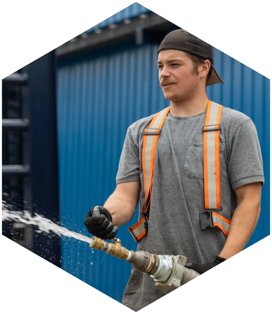 Corestock employee actively testing the  water pressure of a large hose